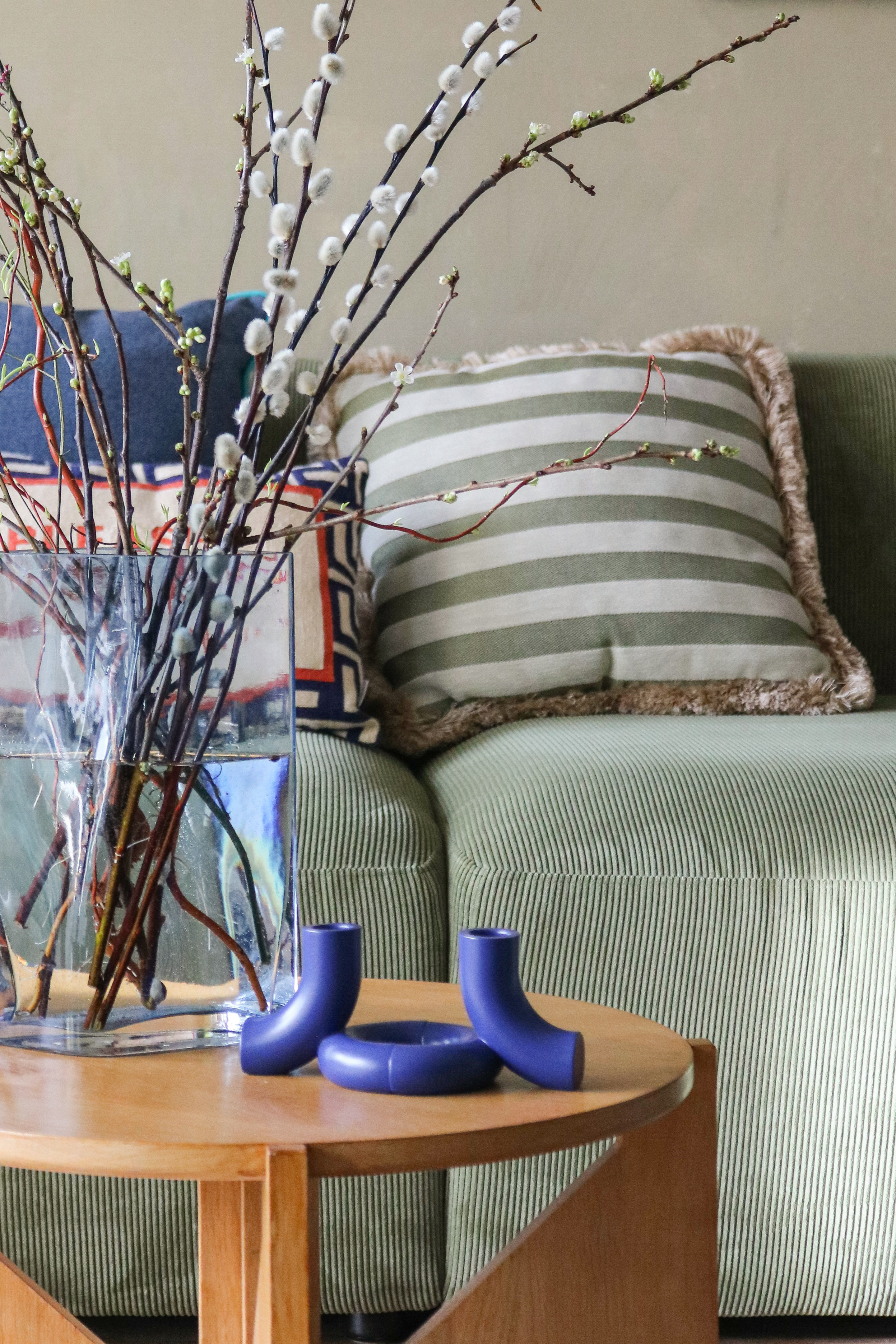 Moderner Beistelltisch mit Zweigen in Glasvase und blauem blomus Kerzenhalter im Wohnzimmer