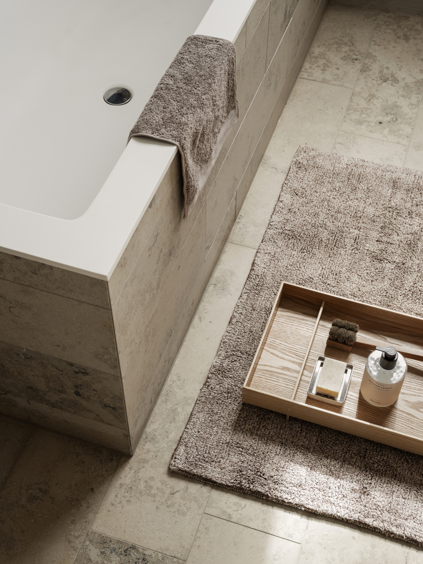 Le plateau en bois ABENTO, accompagné de produits de salle de bain, dont une lotion pour les mains.